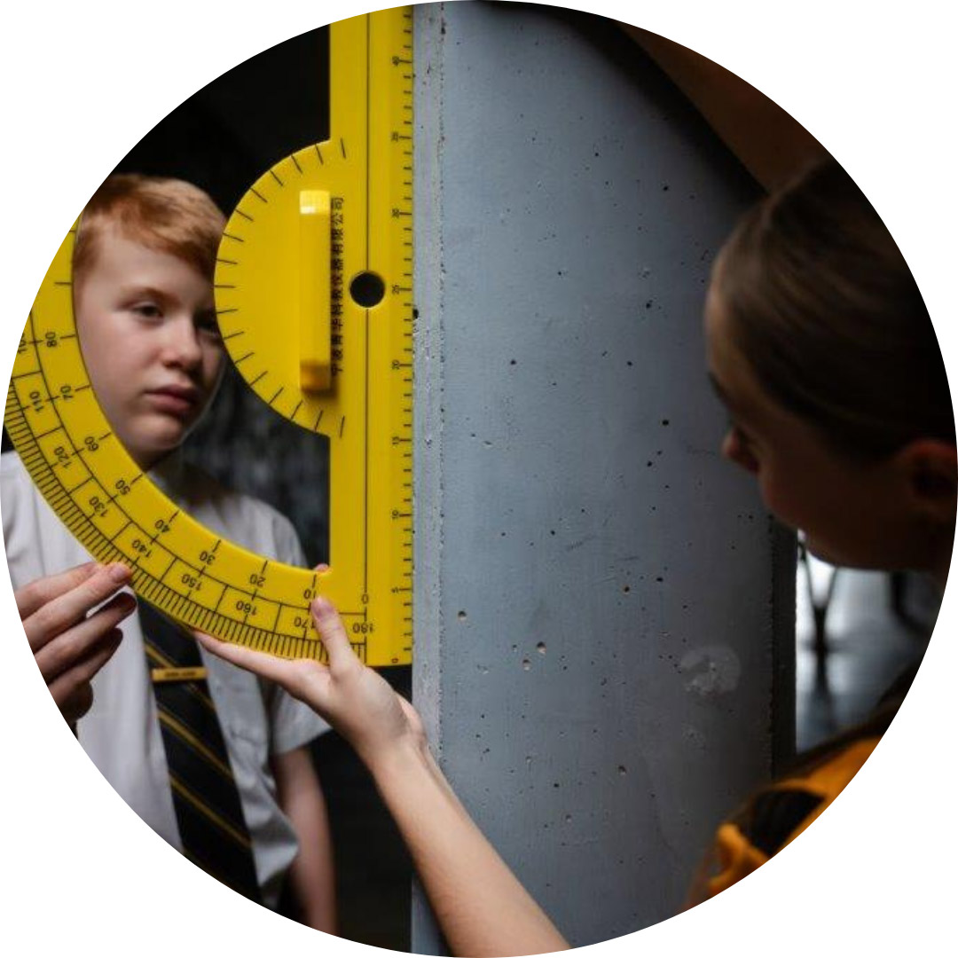 Student looking through large protractor against a wall