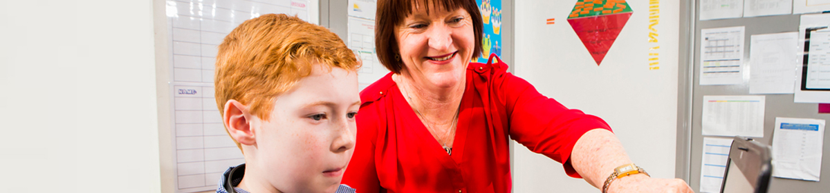 Student and teacher looking at laptop